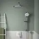 Duschsystem von Ideal Standard mit einem großen, runden Kopfbrause und einer Handbrause, installiert an einer hellgrünen Wand mit weißen Fliesen.